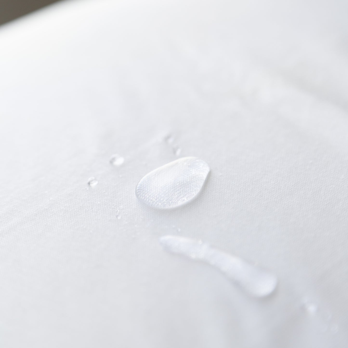 Close-up of a water droplet on a white cotton waterproof pillow