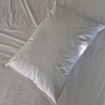White waterproof cotton pillow laying on a white bed sheet