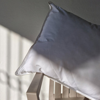 White waterproof cotton pillow sitting on a grey outdoor armchair with a neutral background